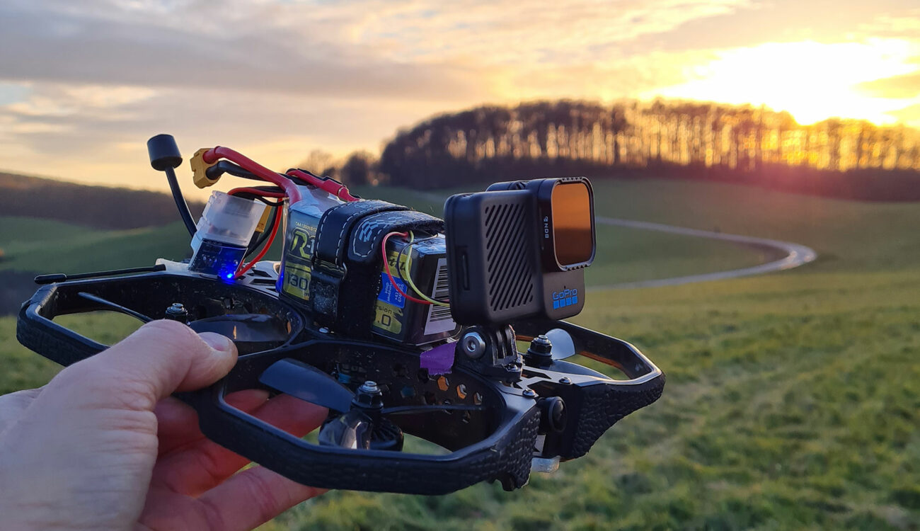 Drone Cinewhoop FPV con GoPro montada, sostenido al atardecer en un campo