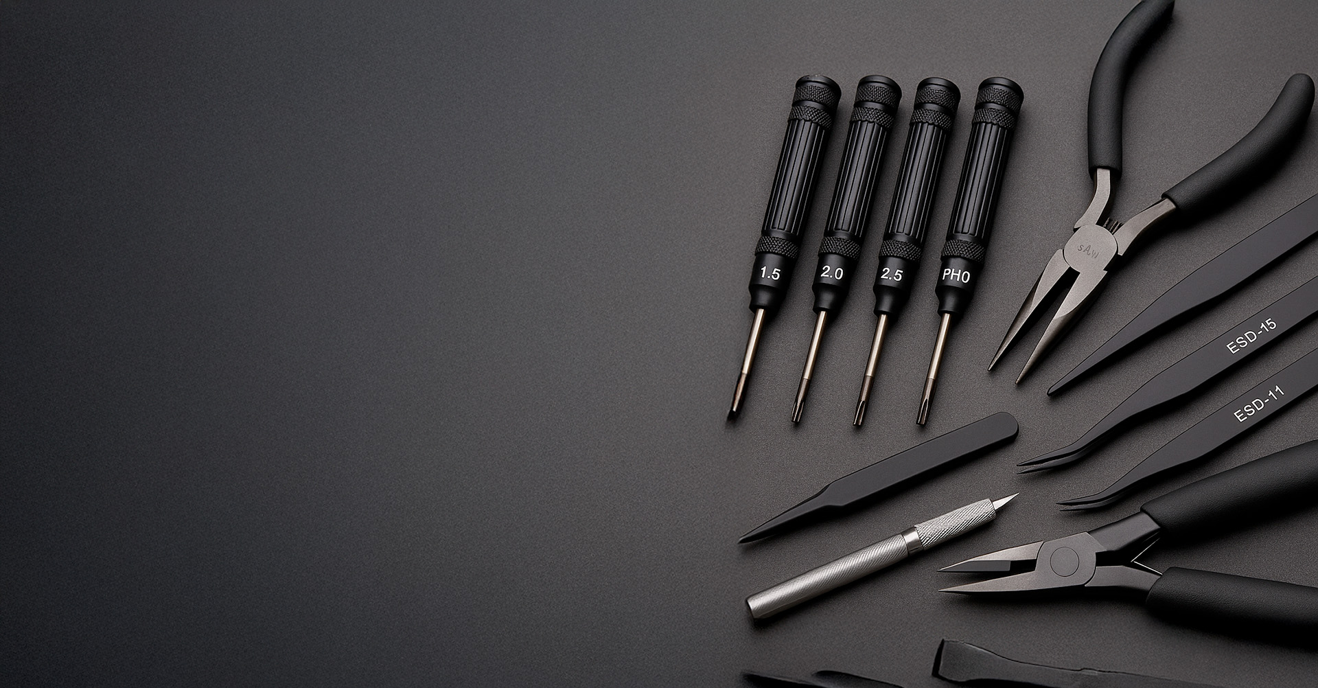 Kit de herramientas de precisión para reparar drones con destornilladores, pinzas y alicates organizados sobre fondo oscuro.